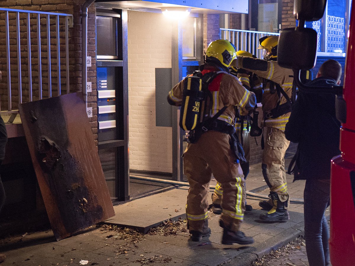 Brandweer blust kleine brand bij portiekwoning; bewoner ademt rook in