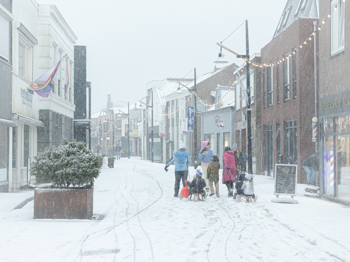 Kinderen spelen in sneeuw; anderen genieten van winterse plaatjes